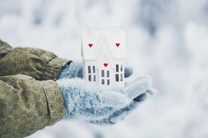 A gloved hand holding an image of a home.